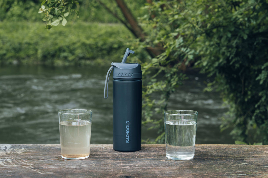 Bachgold® Outdoor Wasserfilter mit ungefilterten und gefilterten Wasser am Fluss als Beispiel für sauberes Trinkwasser unterwegs.