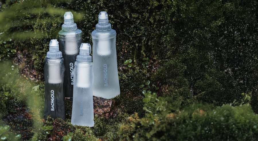 Bachgold® Squeeze Outdoor Water Filter in grey and white, four bottles on moss