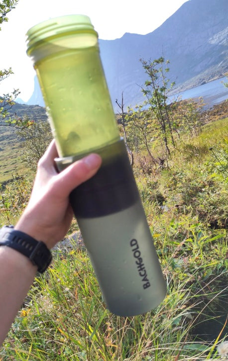 Gefiltertes Wasser in der zweistufigen Flasche vor Bergkulisse